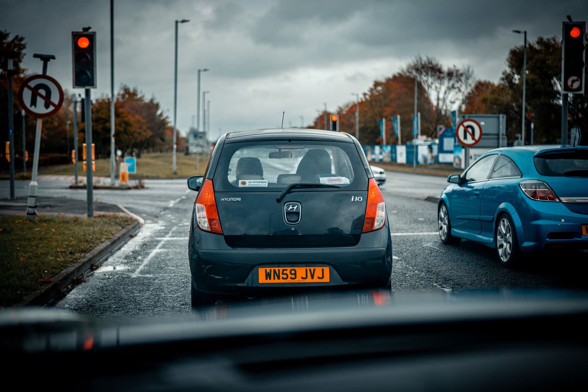 A wet junction seen from the driver's seat, traffic lights on red